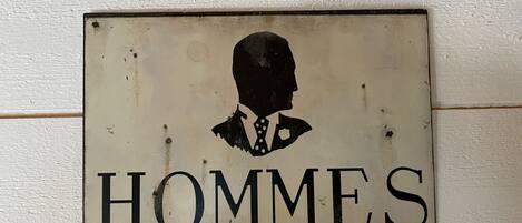 A sign with a silhouette of a man and the word "HOMMES" on a white background.