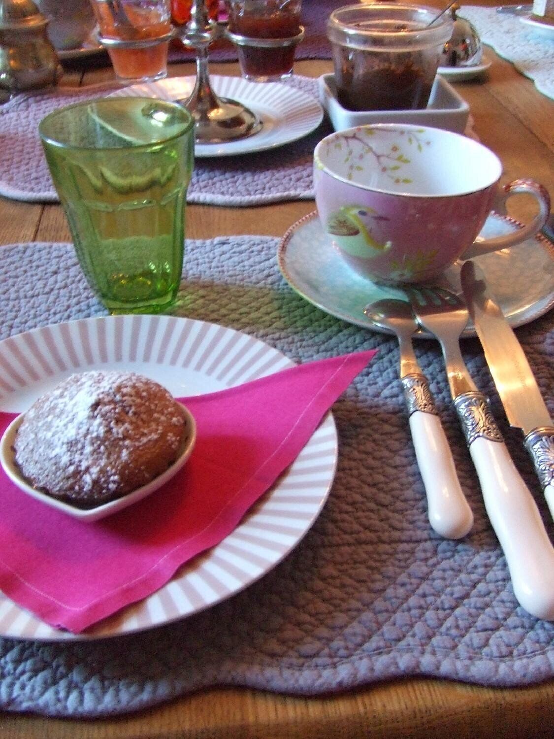 A table with a plate of food, a cup, and a glass.