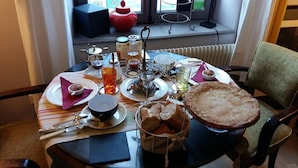 Een gedekte eettafel met diverse gerechten, waaronder brood, een theepot en bijgerechten.