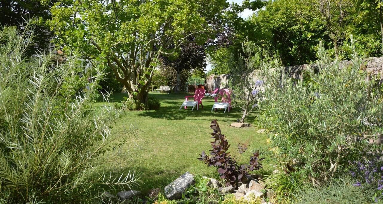 A garden with a lawn, trees, and a stone wall.