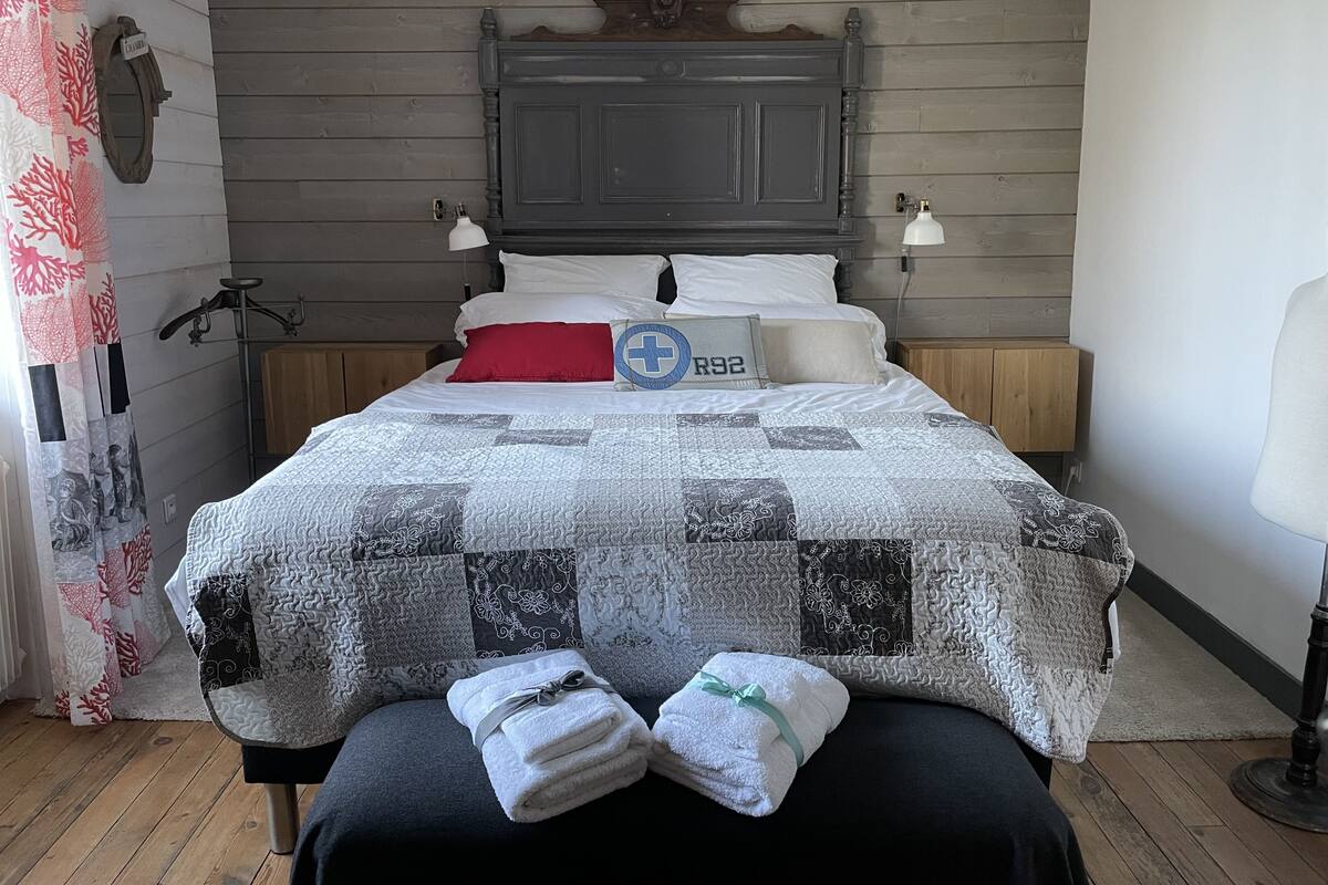 Een net opgemaakt bed met een sprei, kussens en een nachtkastje met een lamp.
