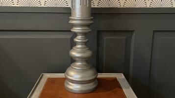 A table lamp with a dark shade on a wooden table with a drawer.