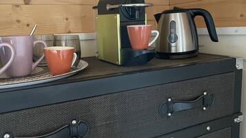 Uma cozinha compacta com cafeteira, chaleira e duas xícaras em uma bancada.