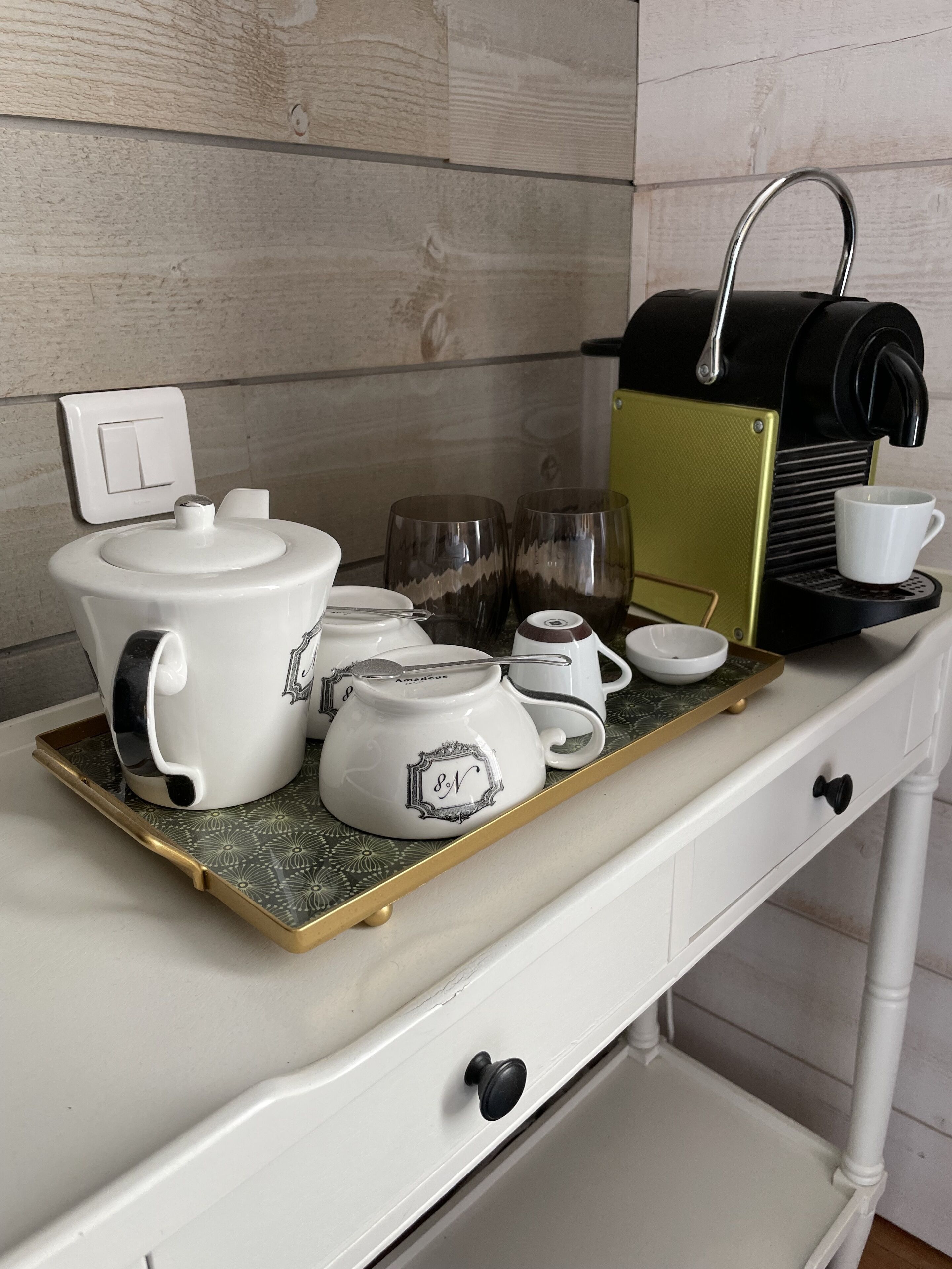 A kitchen counter with a coffee maker, teapot, cups, and a tray.