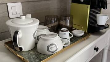 A kitchen counter with a coffee maker, teapot, cups, and a tray.