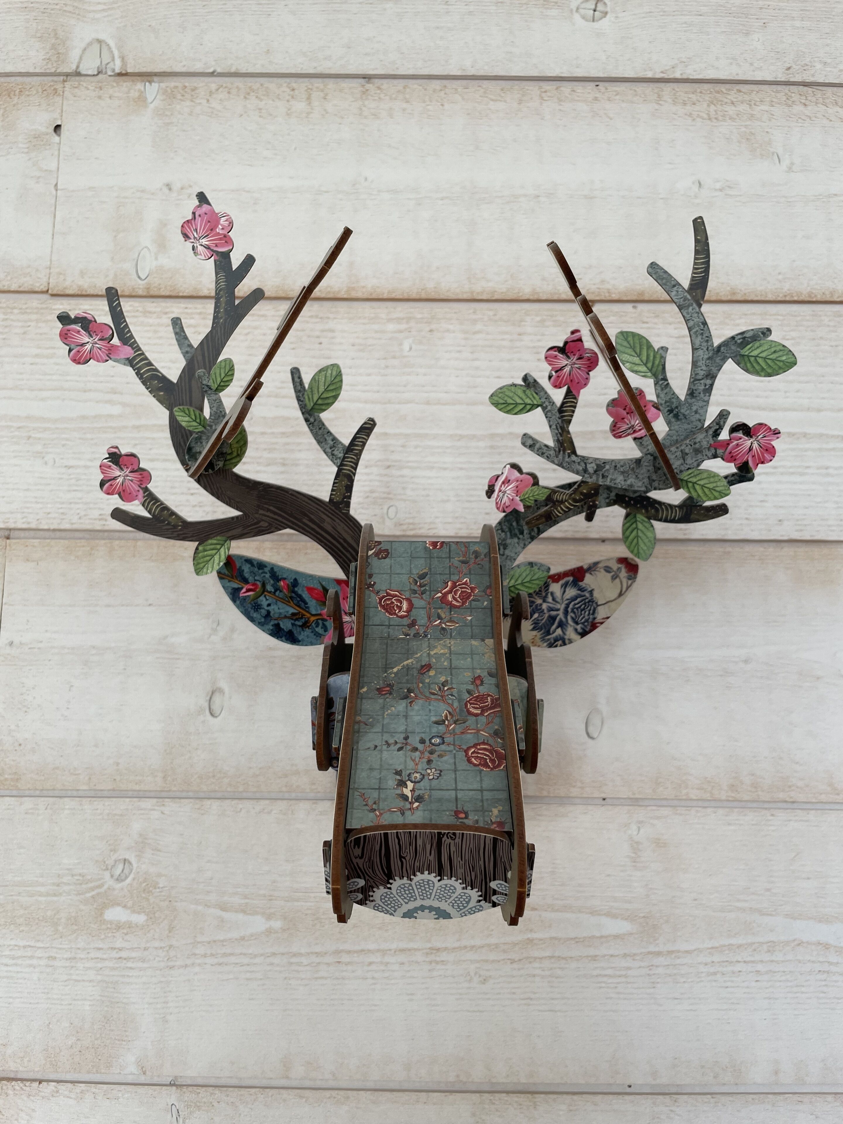 Un élément décoratif à fixer au mur, orné de motifs floraux et de branches.