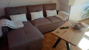 En moderne stue med en brun hjørnesofa, et træsofabord og et billede på væggen.
