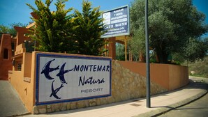 Schild für das Montemar Nature Resort mit einem Delphin-Logo und einer Steinmauer.