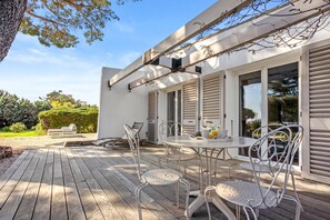 A wooden deck with outdoor seating, a table with chairs, and a pergola with climbing plants. - Villa 'Artemis' with Sea View, Wi-Fi, and Air Conditioning in Grimaud (Grimaud)