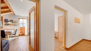 Une pièce avec un plancher en bois, une porte, un petit bureau et une chaise.