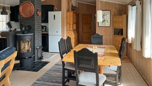 A cozy kitchen with a wood stove, black cabinets, and a dining area with a wooden table and chairs. - 3 bedroom stunning home in Uvdal (Uvdal)