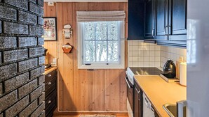 A compact kitchen with wooden walls, a window with a view of trees, and a brick wall on one side. - 3 bedroom stunning home in Uvdal (Uvdal)