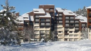 Ein mehrstöckiges Gebäude mit modernem architektonischen Design, das eine Kombination aus rechteckigen und quadratischen Fenstern sowie ein Flachdach aufweist.