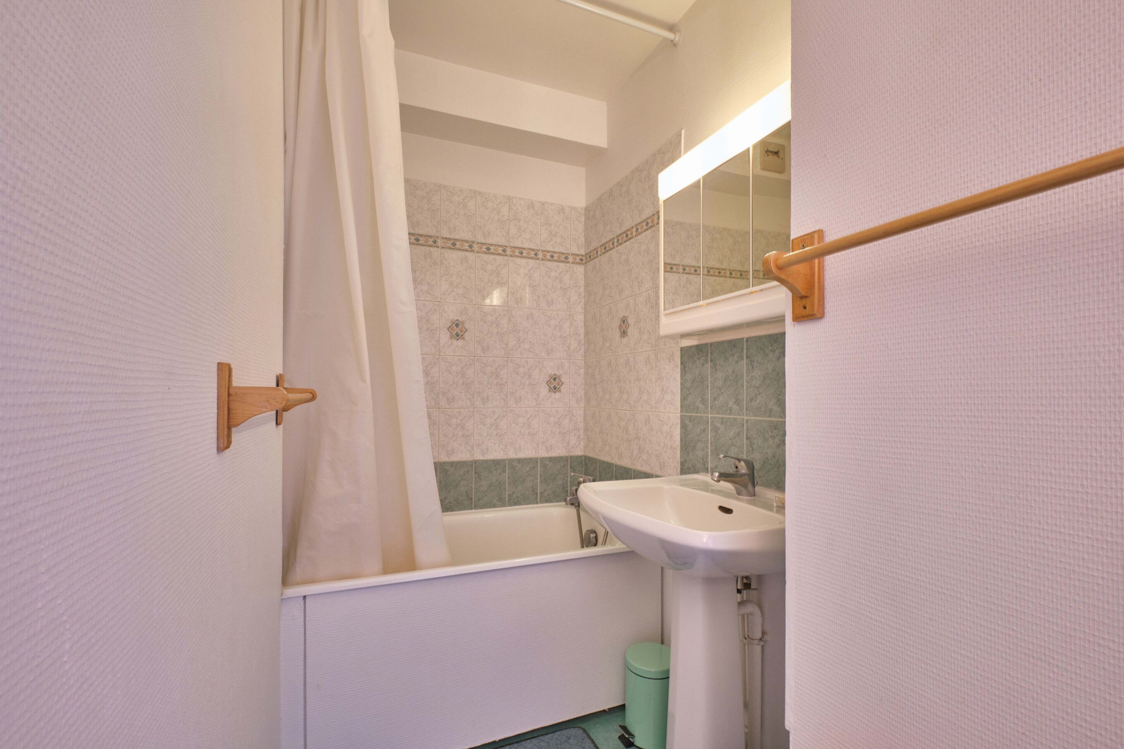 A bathroom with a bathtub, sink, and a mirror.