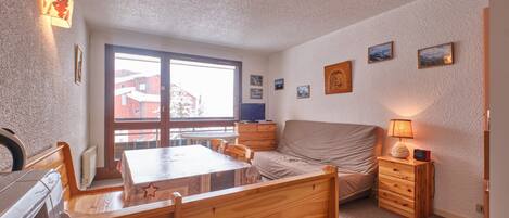 Una stanza con un tavolo da pranzo in legno, sedie, un divano, un piccolo armadio e una finestra vista edifici.