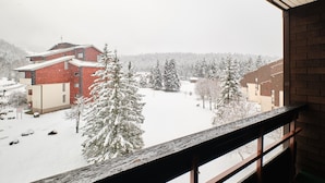 Aussicht vom Fenster auf eine verschneite Landschaft mit Gebäuden und Bäumen.