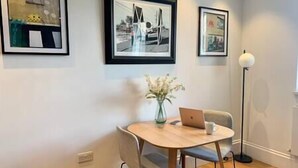 A dining area with a round table, chairs, a laptop, and a vase of flowers. - Elegant Period Apartment for 3, Free Parking, Central (Reading)