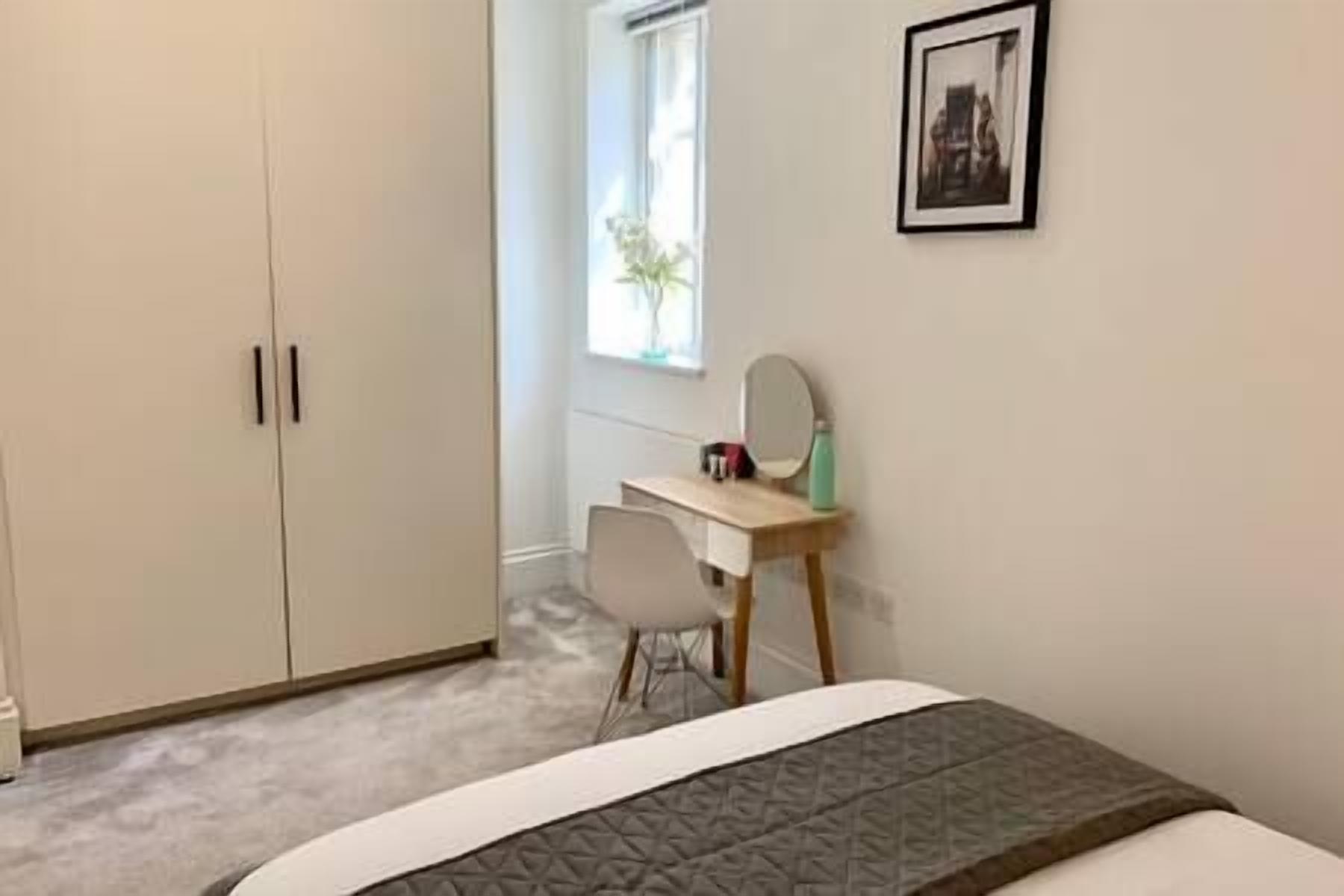 Une chambre à coucher avec un lit, un bureau, une chaise, une armoire et une fenêtre.