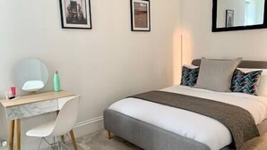 A bedroom with a bed, a desk, and a chair. There are framed pictures on the wall. - Elegant Period Apartment for 3, Free Parking, Central (Reading)