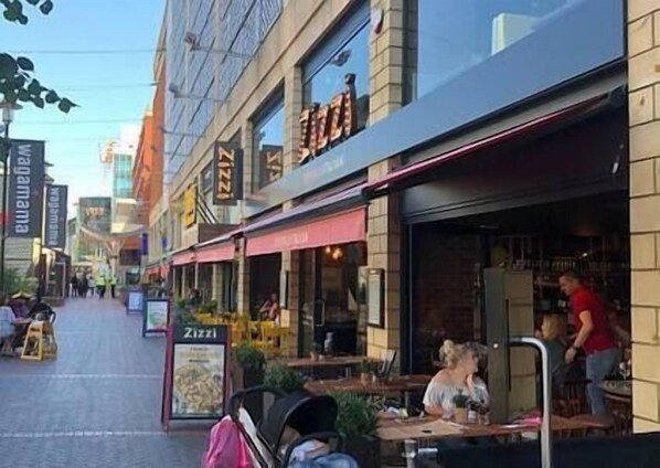A street view with outdoor seating at a restaurant.
