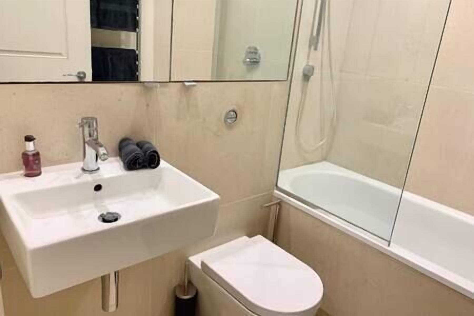 A bathroom with a white sink, a toilet, and a glass-enclosed shower area.
