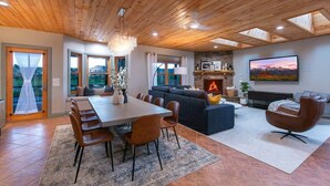 A spacious living area with a fireplace, a dining table, and a large TV. - Casa Del Rio hot tub, sauna, movie theater #020796 (Buena Vista)