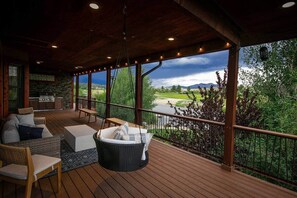 A covered outdoor area with a wooden deck, wicker furniture, and a view of a river and mountains. - Casa Del Rio hot tub, sauna, movie theater #020796 (Buena Vista)