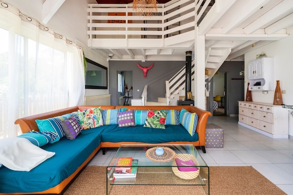 A living room with a sectional sofa, a glass coffee table, and a staircase leading to an upper level.