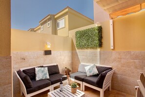 A patio with two sofas, a table, and a wall-mounted light.