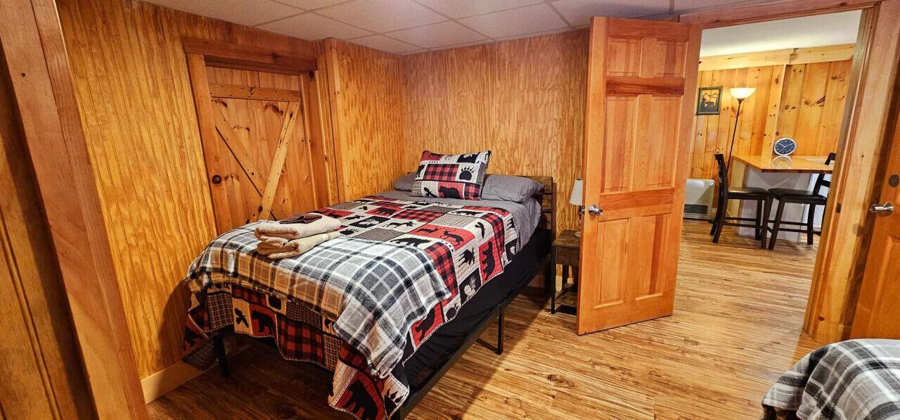 A wooden-paneled room with a bed, a small table, and a chair.