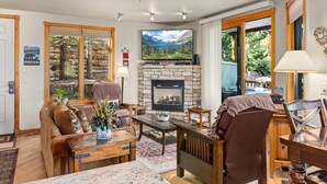A cozy living room with a stone fireplace, a large flat-screen TV, and a comfortable seating area.