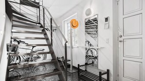 Un escalier moderne avec des rampes en métal, un banc et des vélos rangés au mur.