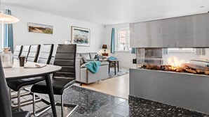 Un salon moderne avec une cheminée, un coin repas avec une table ronde et des chaises, et un canapé.
