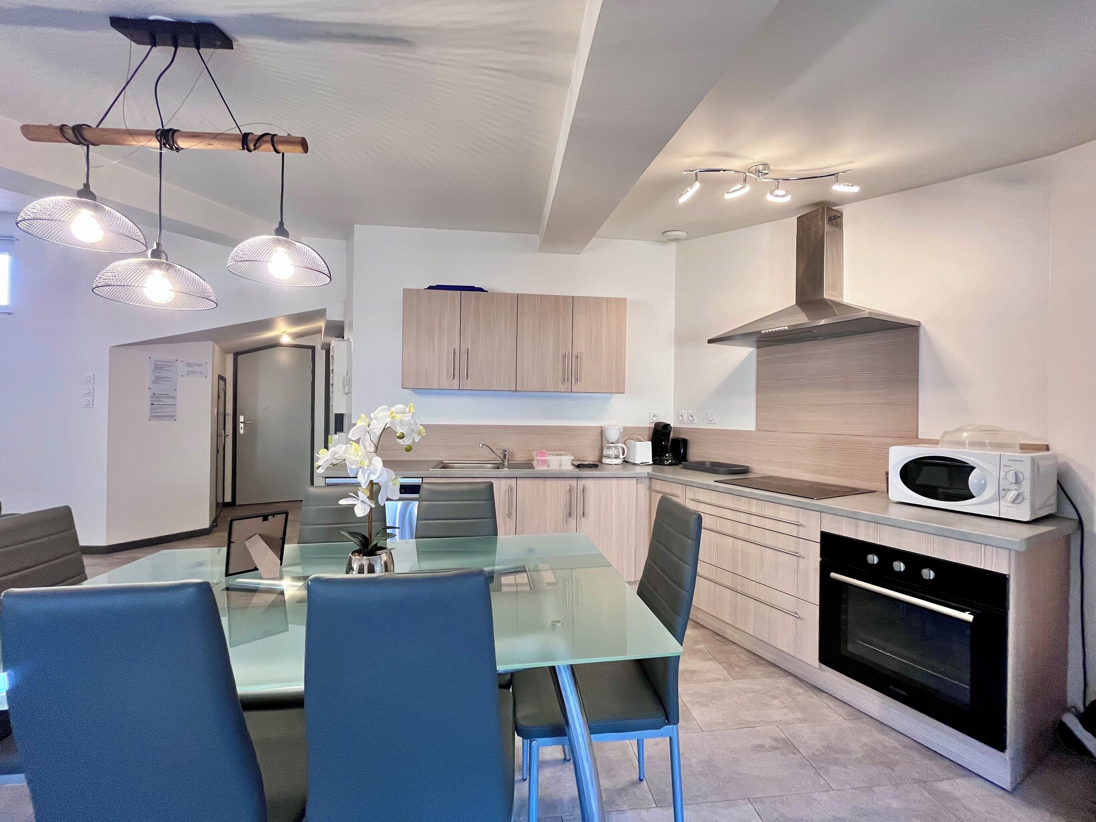 A modern kitchen with a glass dining table, chairs, and a built-in oven.