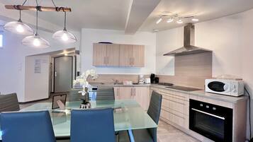 A modern kitchen with a glass dining table, chairs, and a built-in oven.