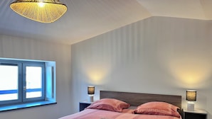 A modern hotel room with a large bed, two bedside lamps, a window with blinds, and a ceiling light fixture. - Chez Isa - Tournon-sur-Rhône (Tournon-sur-Rhône)