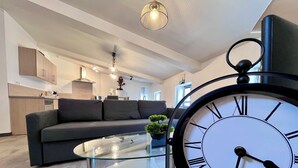 A modern living room with a glass coffee table, a black sofa, and a large wall clock. - Chez Isa - Tournon-sur-Rhône (Tournon-sur-Rhône)