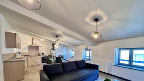 A modern living room with a dark sofa, a glass coffee table, and a dining area with a table and chairs. - Chez Isa - Tournon-sur-Rhône (Tournon-sur-Rhône)