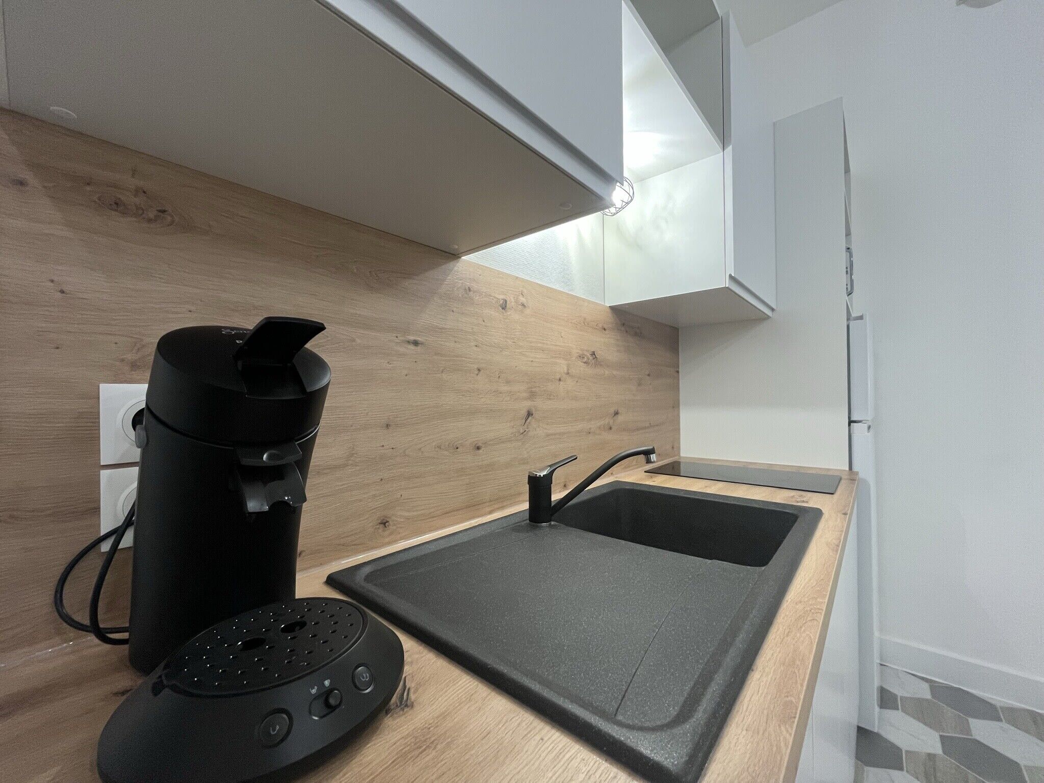Una cocina moderna con encimera de madera, una cafetera negra y una placa de inducción negra.