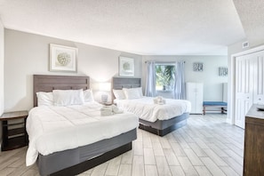 A bedroom with two beds, a bench, a wardrobe, and framed artwork on the walls. - Oceanview Paradise at the Beach (Myrtle Beach)