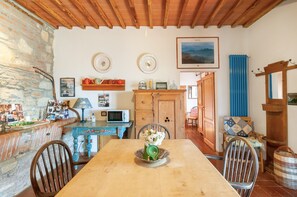 Un coin repas rustique avec une table en bois, des chaises, un buffet bleu et un mur en pierre.