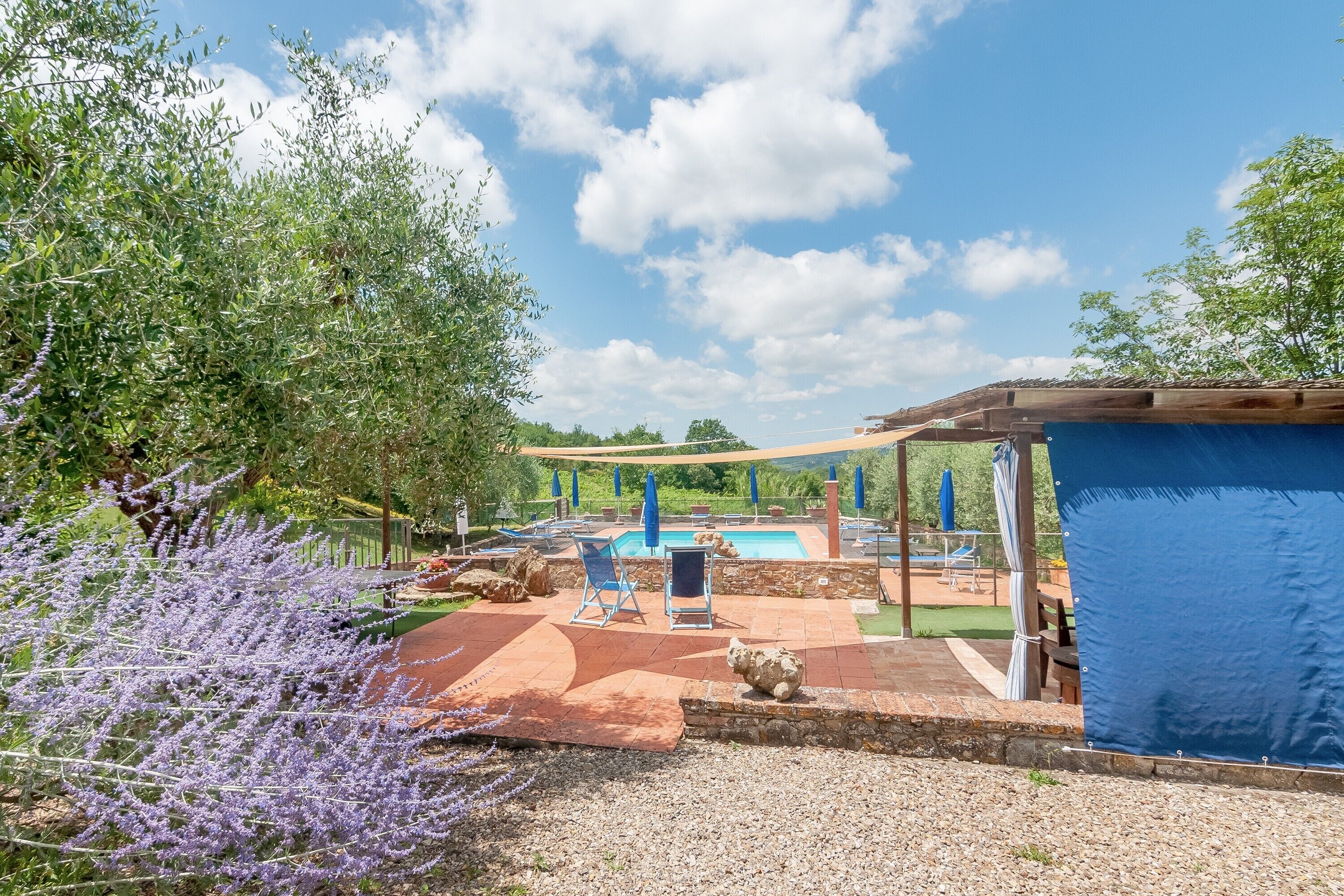 Un área de piscina con sillones de descanso, una pérgola y una zona de estar cubierta.