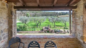 A rustic stone room with a wooden ceiling, a window overlooking a green landscape with trees and a fence. - Agriturismo 'Molinuzzo - Lisa' with Shared Pool, Private Terrace and Wi-Fi (Barberino Tavarnelle)