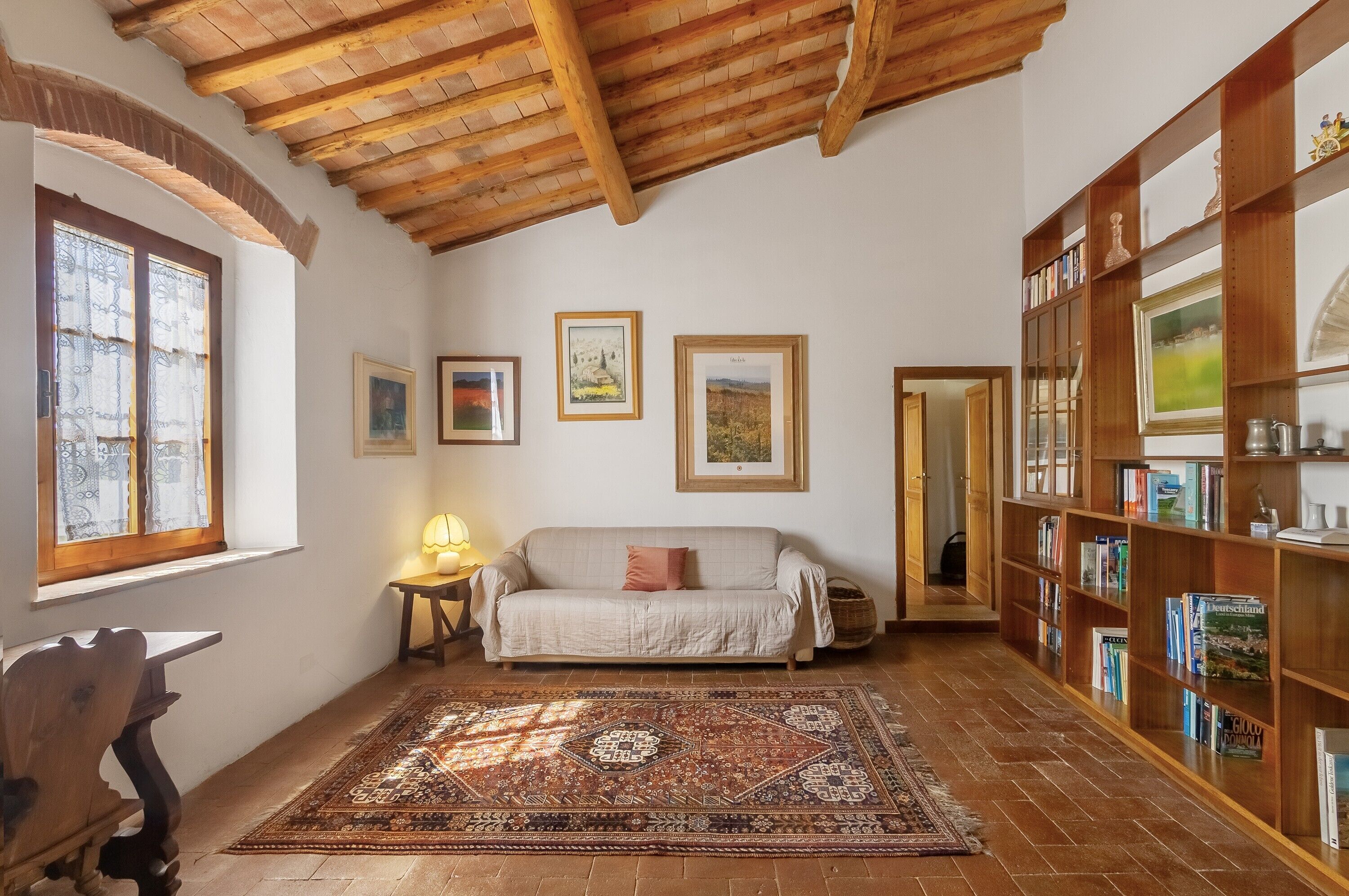 Ein gemütliches Zimmer mit Holzboden, einer Couch, einem Teppich und einem Bücherregal.