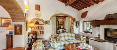 A cozy living room with a checkered sofa, a fireplace, and a ceiling fan.