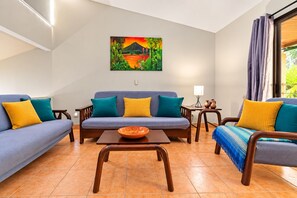 A living room with a sofa set, a coffee table, and a painting on the wall.