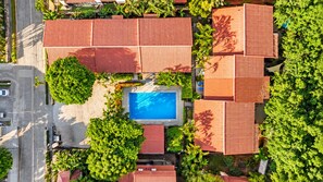 An aerial view of a residential area with multiple houses, a swimming pool, and a road.