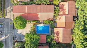 Vista aérea de una propiedad con varias edificaciones, piscina y zonas verdes circundantes.
