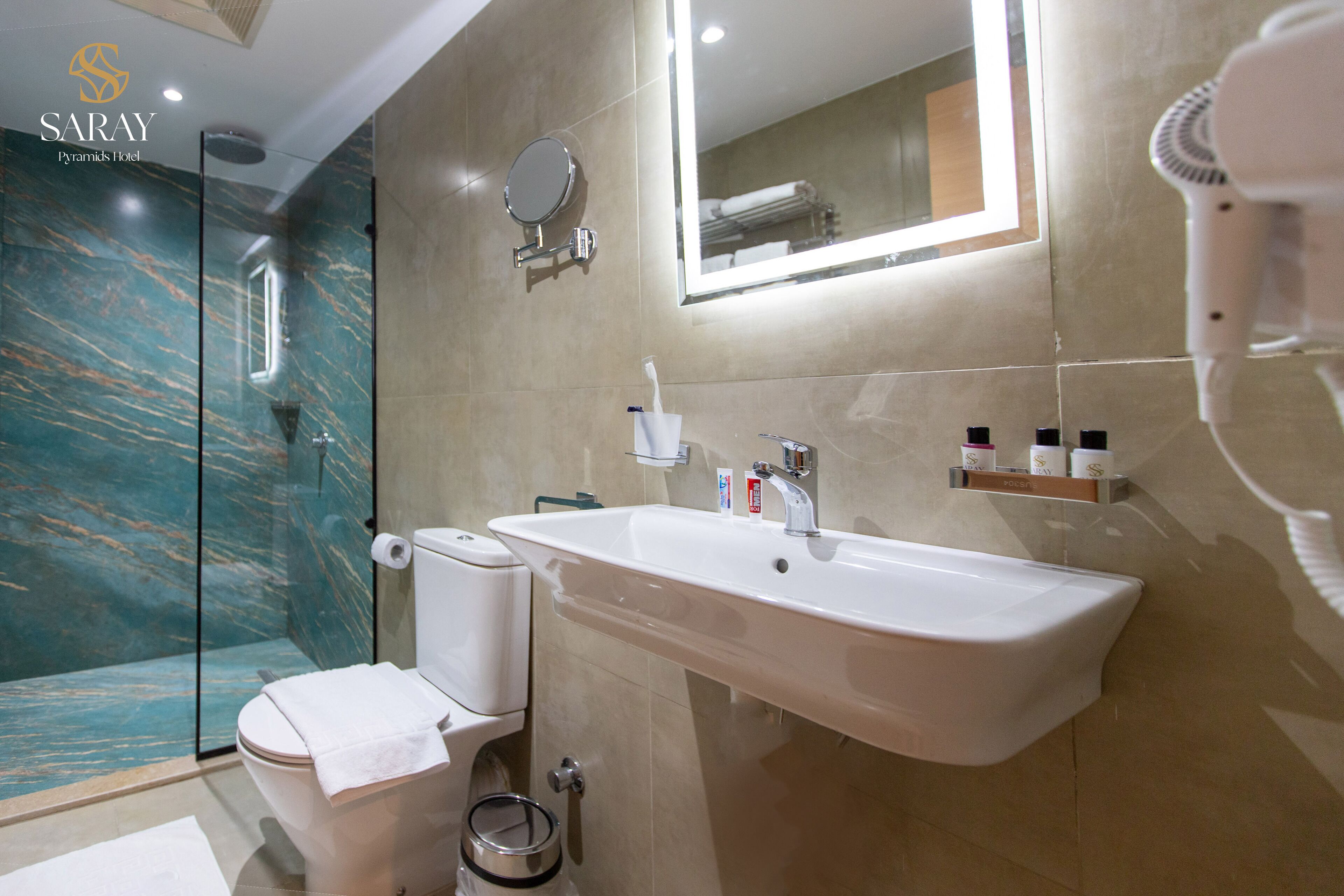 A modern bathroom with a marble shower, a white sink, and a large mirror.