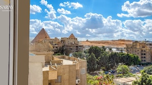 A view of the Pyramids of Giza from a hotel balcony, including the Great Pyramid and the Sphinx, with surrounding buildings and vegetation. - Saray Pyramids & Museum View Hotel (Giza)